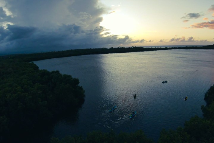 Kayakers on a large lake at sunset, surrounded by forests.