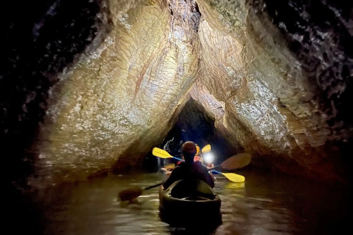 Person kayaking through a narrow cave passage.