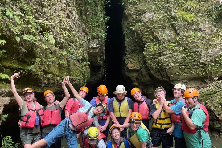Group of people in safety gear posing at a rocky outdoor location.