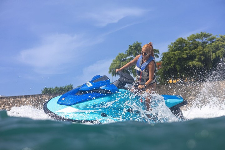 Person riding a blue jet ski on the water with a clear sky.
